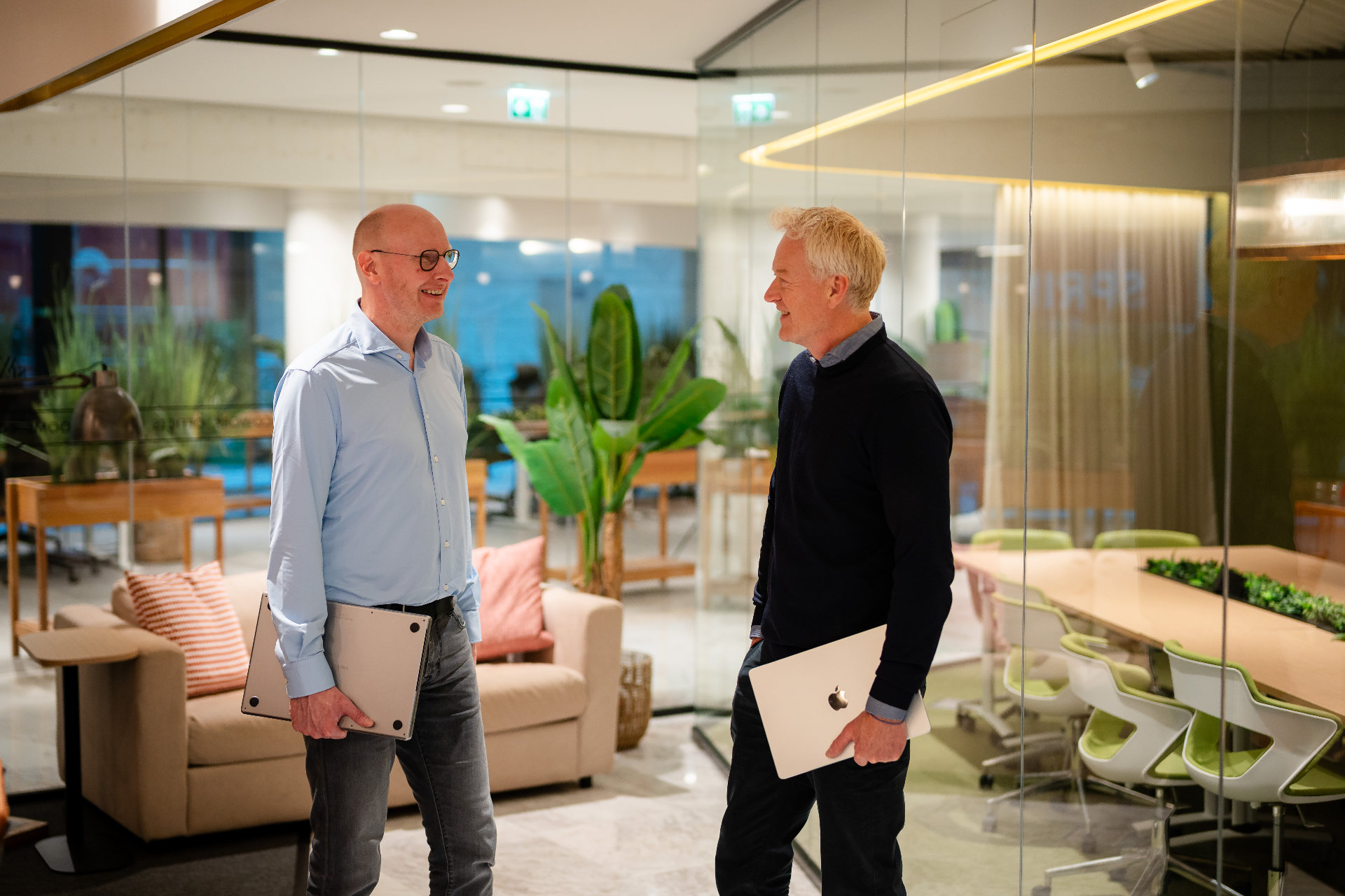 Twee Amaii teamleden in staand werkoverleg met laptops in de hand